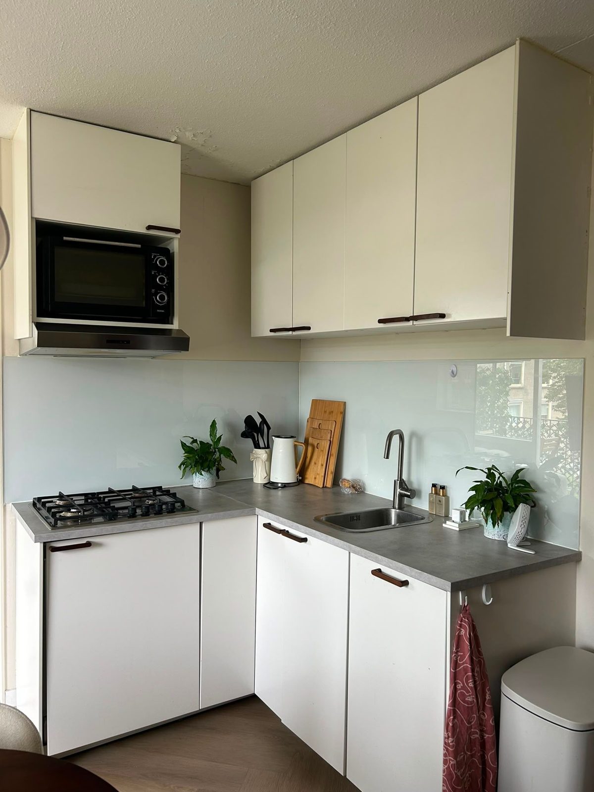 Hoekkeuken met grijs werkblad en lichtblauwe glazen achterwand voor het wrappen, Amsterdam-Oost